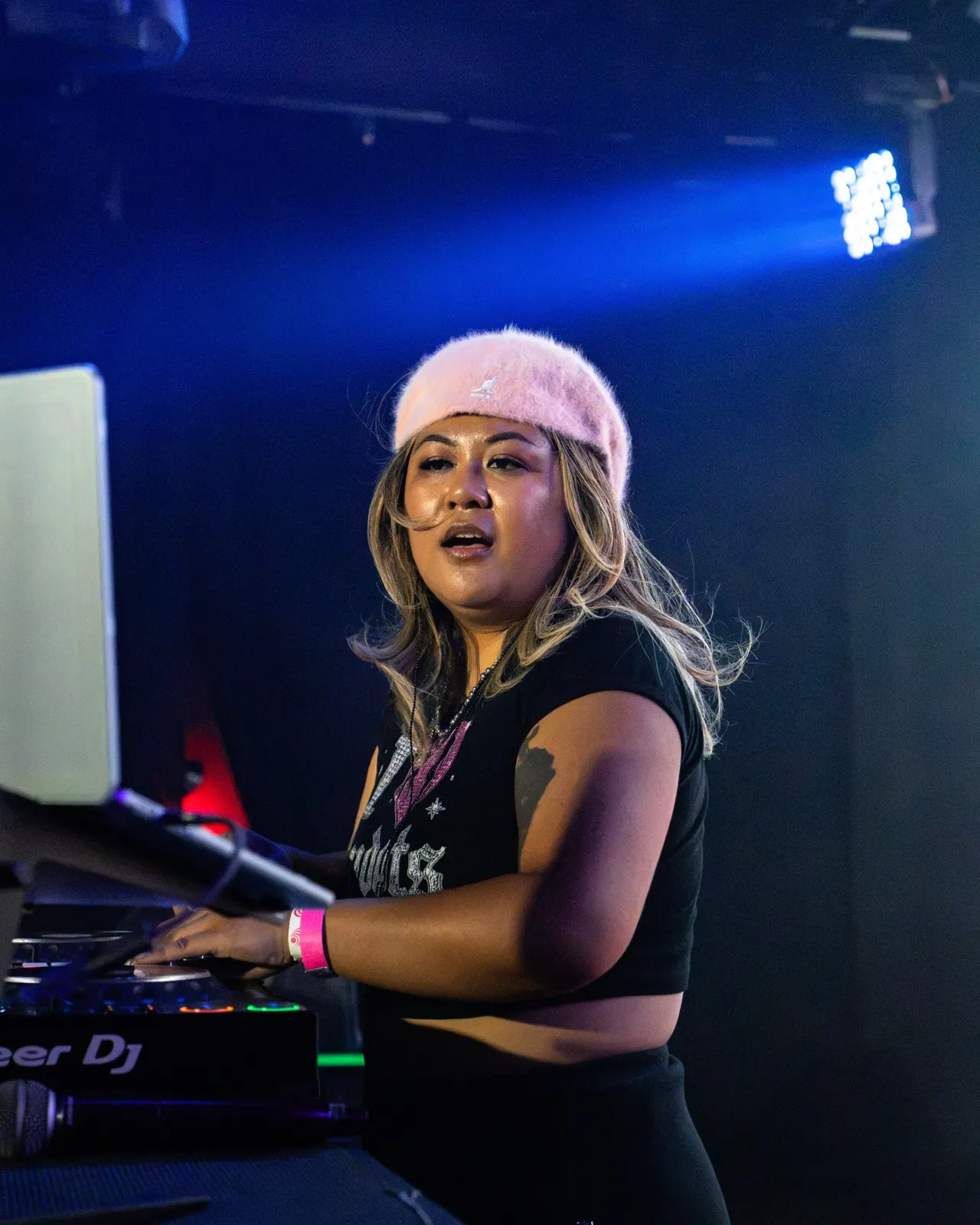 DJ Trixy mixing under stage lights at The Midway